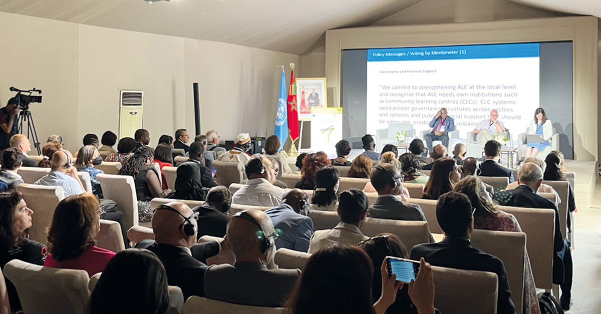 Teilnehmer und Teilnehmerinnen beobachten in einem Seminarraum ein Panel an der in Marrakesch stattfindenden CONFINTEA, die Resultate vorzuweisen hat.