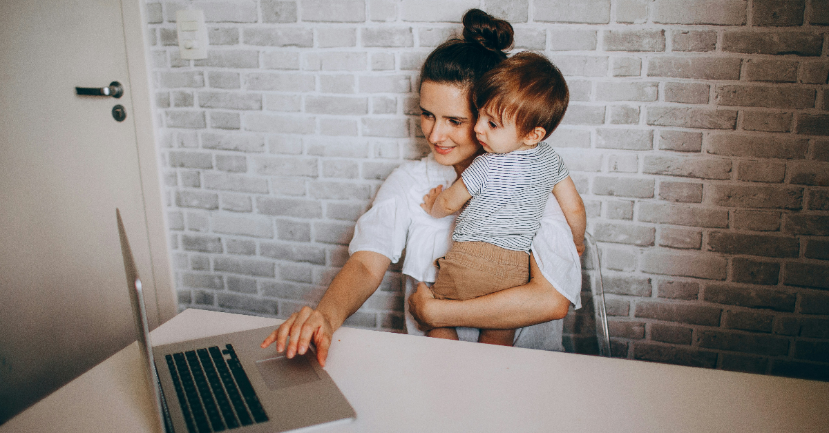 Frau mit Kleinkind auf dem Arm am Computer